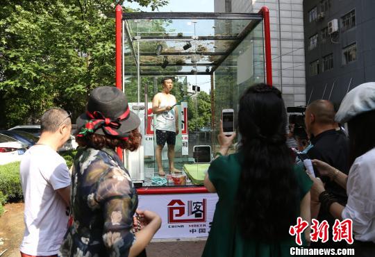 图为创业者安鸿先生在透明玻璃房子里用手机直播自己24小时生活。 张畅 摄