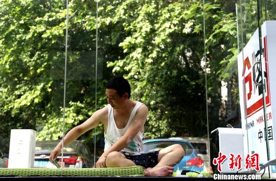 图为创业者安鸿先生在透明玻璃房子里用手机直播自己24小时生活,100天里他要完成项目计划书、团队建设、资本对接创业的全过程。 张畅 摄