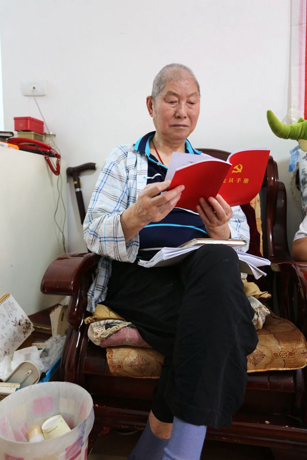 7月1日，朱德超在《党员手册》上查看自己每月委托老伴儿交纳的党费情况。