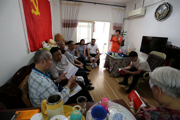 7月1日，被伴儿搀扶到客厅沙发上坐着的朱德超仔细阅读组织带给他的党章等学习资料。