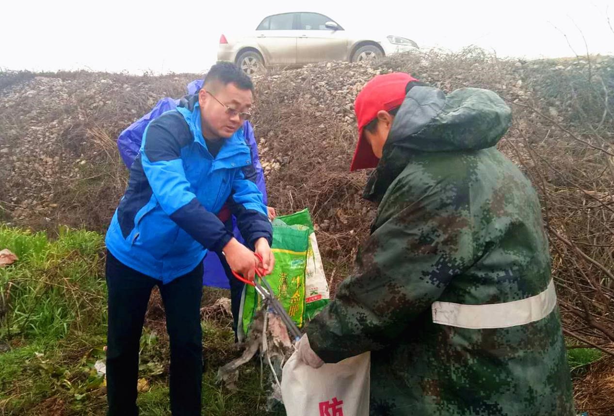 还地桥镇党委书记石国栋与志愿者一起清除湖边石缝中的垃圾.