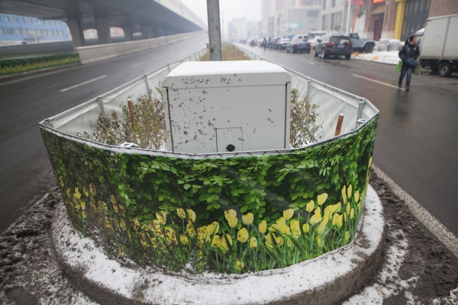 长春街头现仿真绿化带 塑料布上画逼真树木