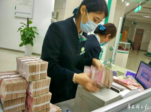 银行工作人员戴着口罩清理发霉的钱.