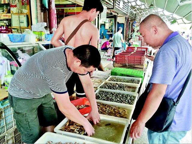 图为:一位市民在华南海鲜市场购买海鲜记者曹磊摄从去年夏天开始回升