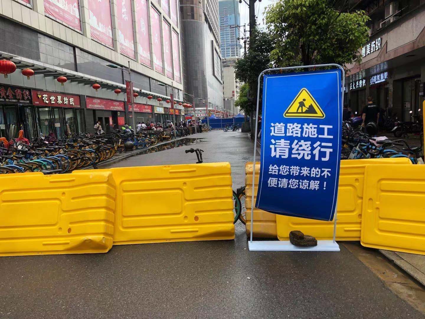 路段已经被围挡起来,围挡上挂有"道路施工,请绕行"的字样,现场正在