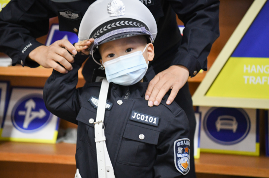 换上警服,戴上警帽,在警旗前,穆穆在交警叔叔的指导下,对着旗帜敬礼