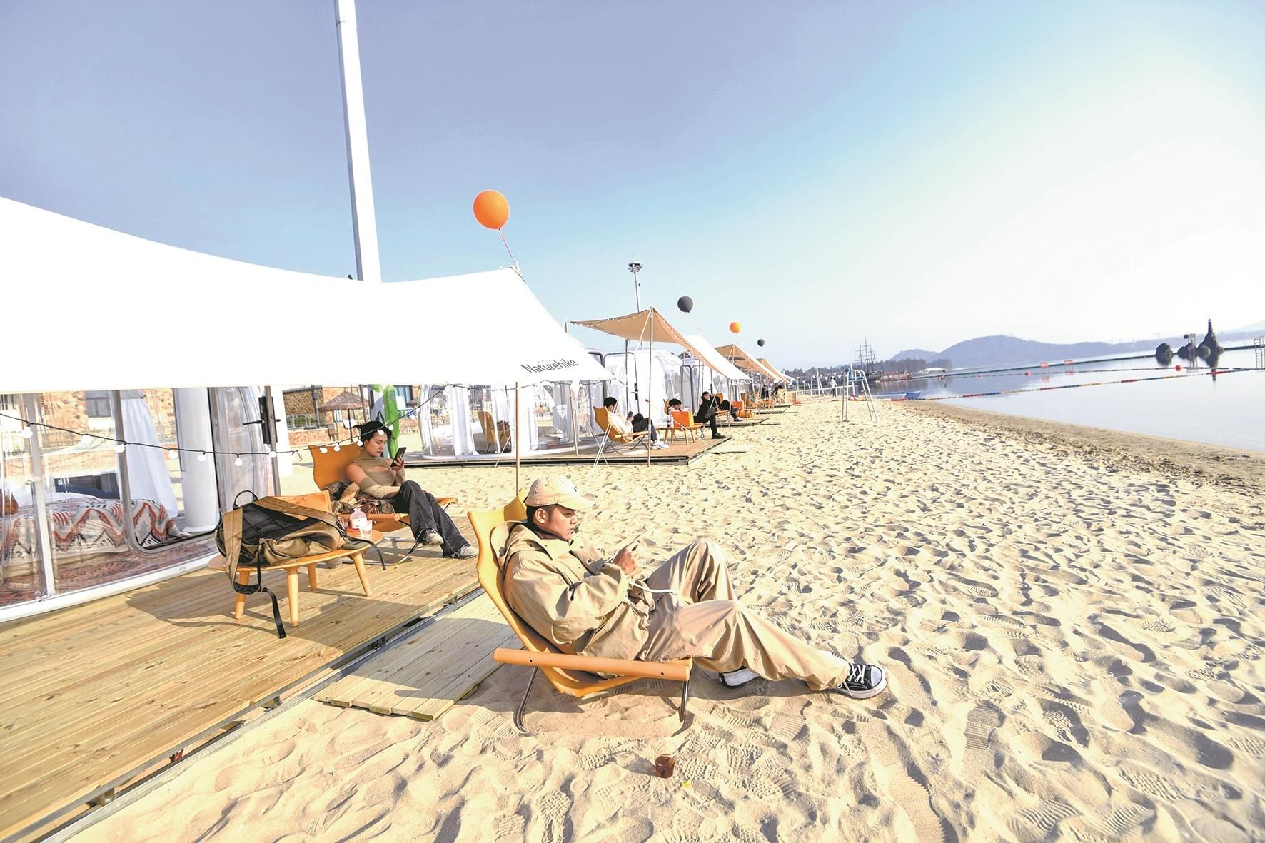 在东湖沙滩,游客躺在沙滩上享受着日光浴,宛如来到三亚的热带海滩