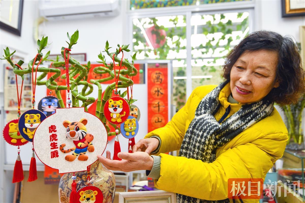 制作布艺堆绣的底板,将不同颜色的布剪,缝,绣,贴出丰富多样的虎像作品