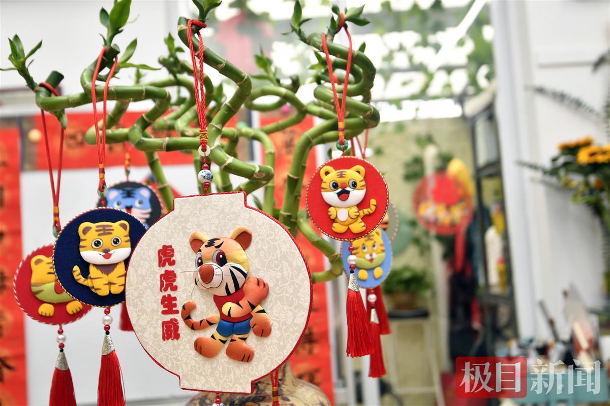 制作布艺堆绣的底板,将不同颜色的布剪,缝,绣,贴出丰富多样的虎像作品