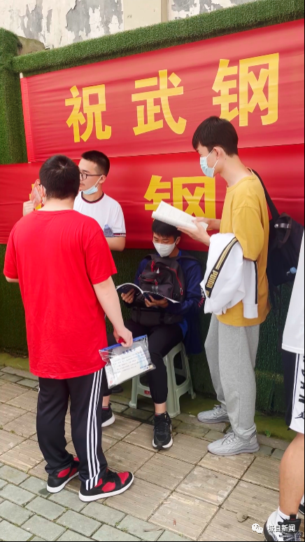 武汉市武钢三中考点前,老师正在为学生发放身份证.