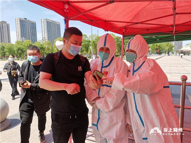 在荆州火车站出站口,志愿者正在查看所有出站旅客的健康码,行程卡以及