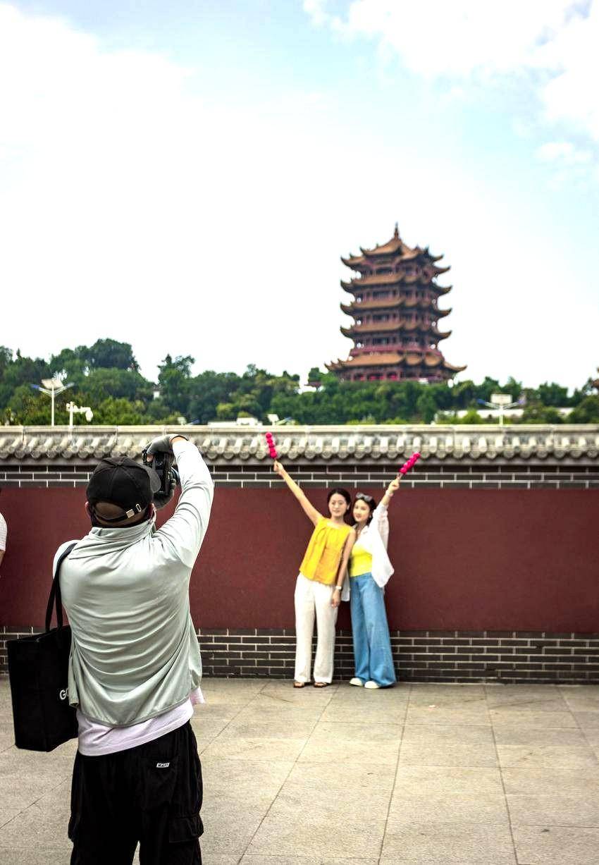 武汉地铁5号线司门口黄鹤楼站外的红墙下，不少游客赶来与黄鹤楼合影。