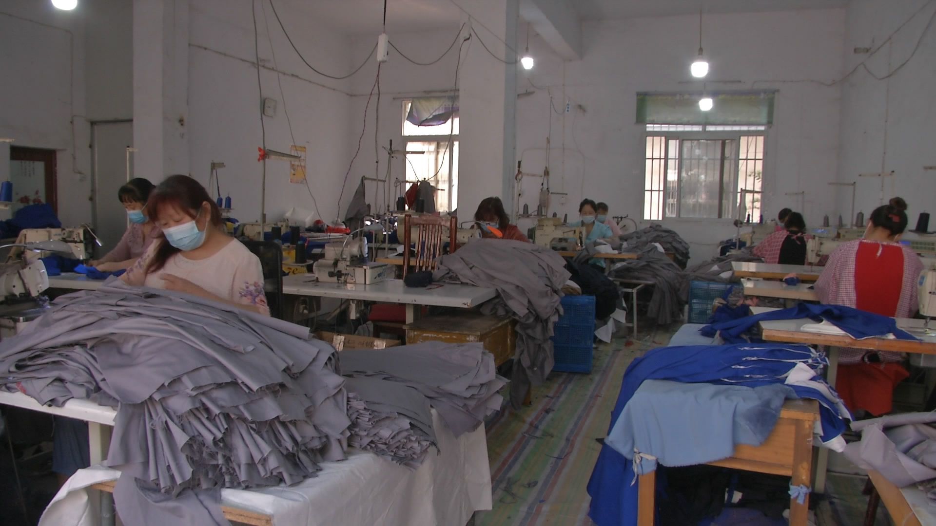 这里流水线上的工人们正忙着裁剪,熨烫,走线,装箱,厂长杨合俊则在车间