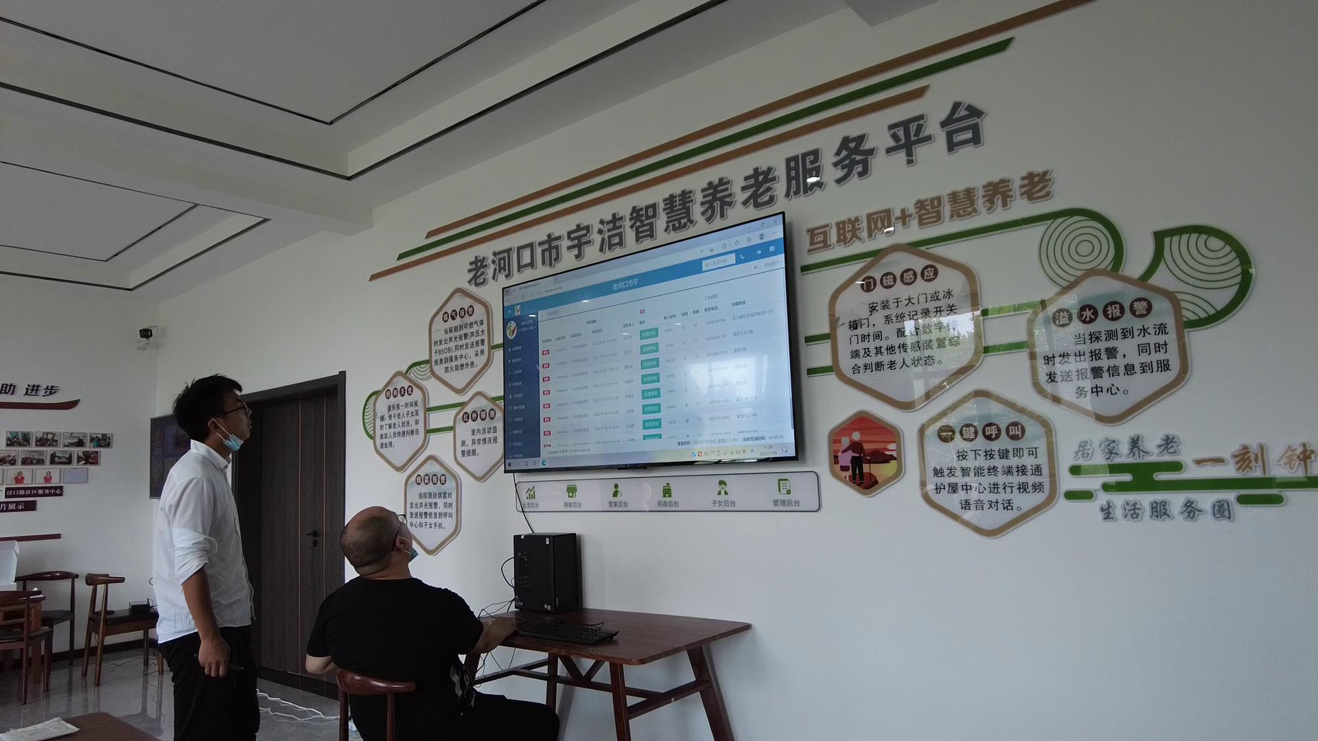 "市宇洁智慧养老服务中心负责人范俊辉耐心地向王成群讲解着呼叫终端