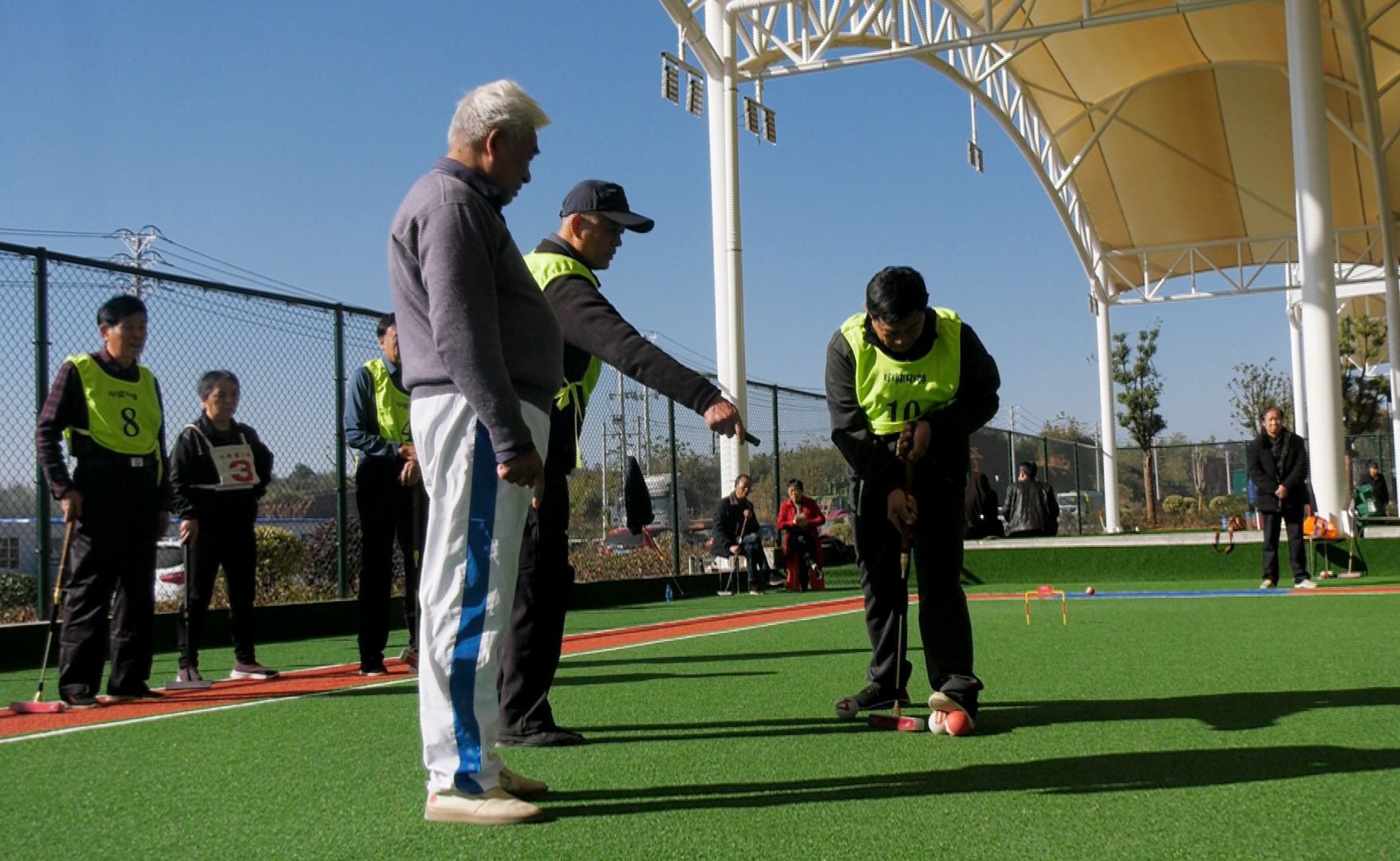 门球运动被称为"平民的高尔夫",是在平地或草坪上,用木槌击打球穿过