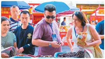 海南自贸港全岛封关运作后，免签政策叠加入境退税便利，推动入境游热度攀升。海口市中山路骑楼老街商铺纷纷推出多语种服务，让外国游客切身感受海南国际旅游消费中心的蓬勃活力。图为外国游客在选购当地特色美食。张 茂摄（人民视觉）