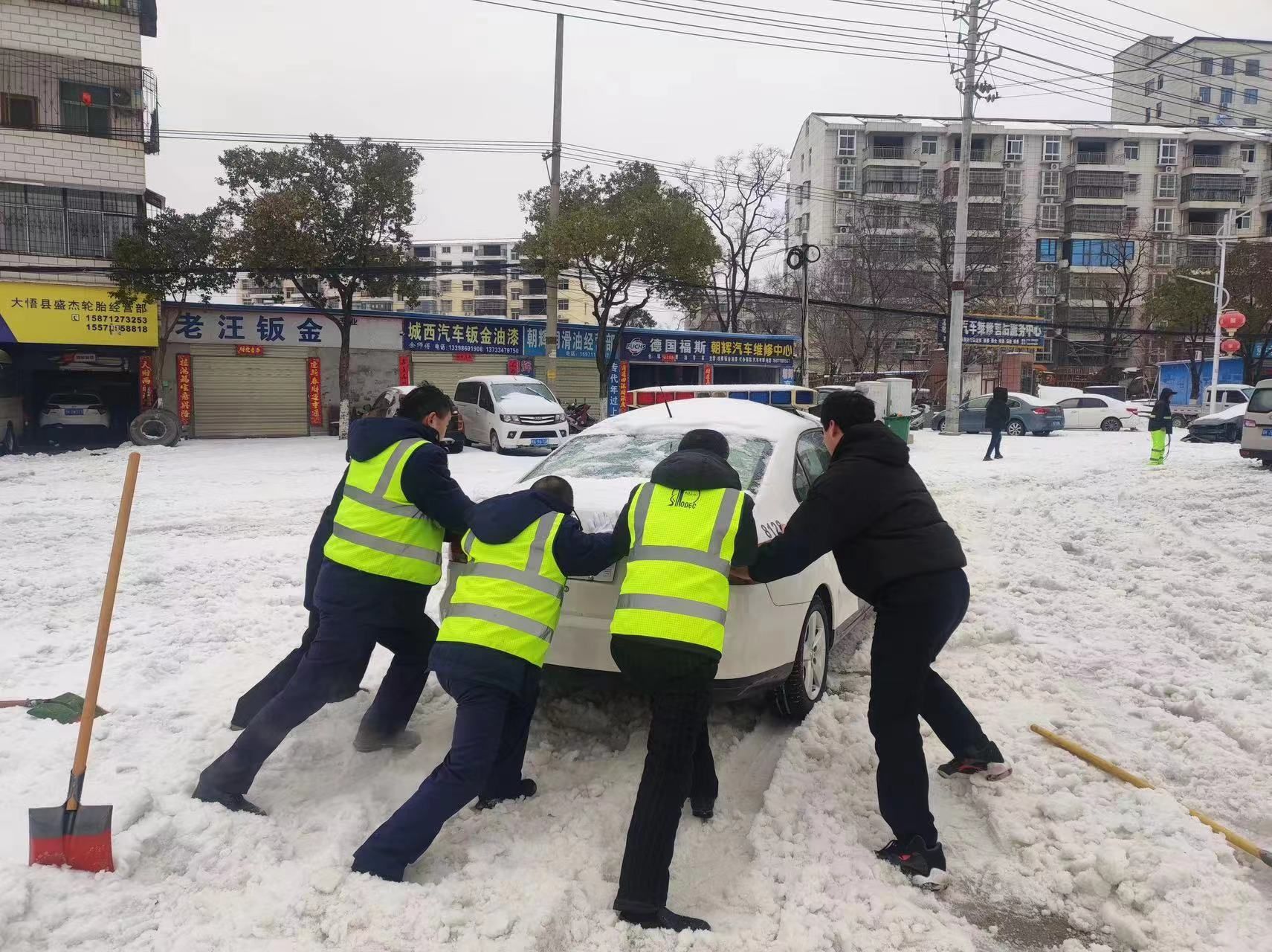 一辆交警警车来加油站加完油,出站时被陷入冰雪中,机关党团志愿帮扶者