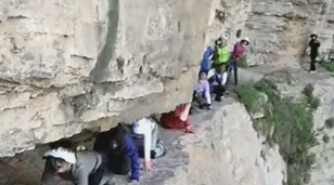 游客无保护措施爬着过悬崖？当地回应