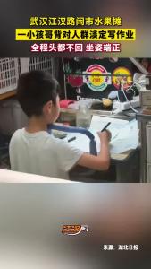 武汉江汉路闹市水果摊，一小孩哥背对人群淡定写作业！