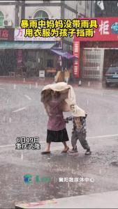 暴雨中妈妈没带雨具用衣服为孩子挡雨
