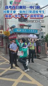 高考首日襄阳一中门前，民警手拿一束向日葵迎接考生，寓意一举夺“葵”前程似锦。